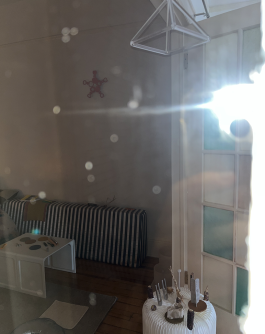 A room lit by camera flash through the glass door contains sound instruments such as tuning forks and a crystal pyramid.